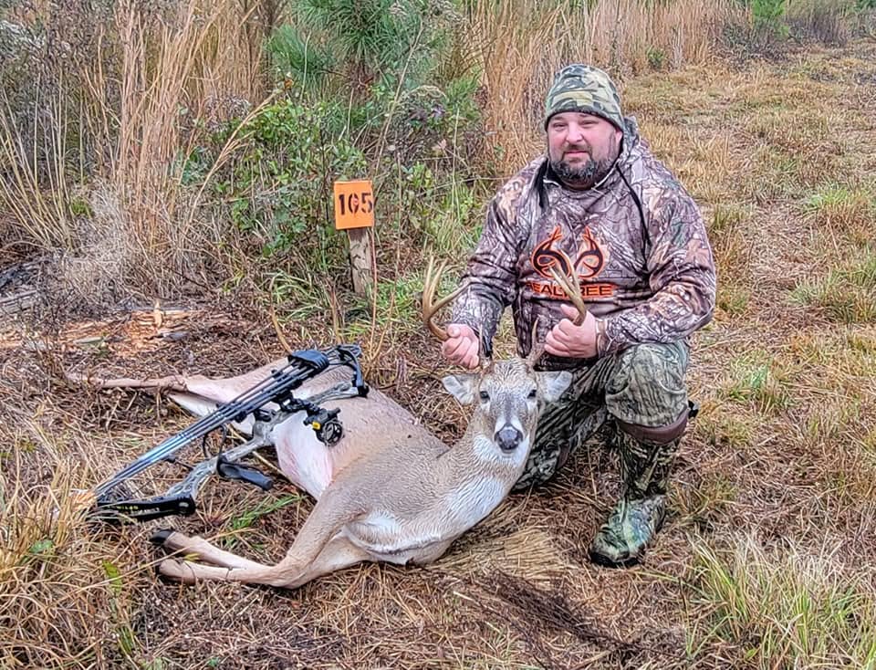 Kevin kneeling beside a harvested deer after a hunt